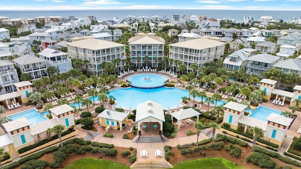 Um resort com piscina central, vários edifícios e vista para o oceano.