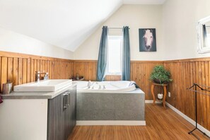 Une salle de bain moderne avec une baignoire sur pieds, un lavabo et un lambris en bois sur les murs.
