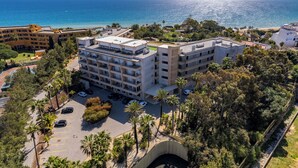 Un hotel de varios pisos con balcones que dan a una playa y al mar.