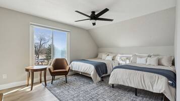A bedroom with two beds, a ceiling fan, a window, and a small table.
