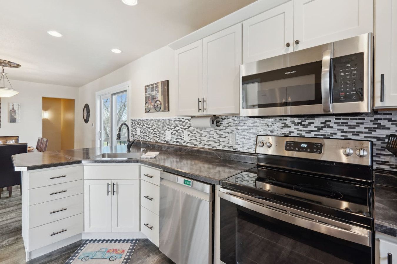 A modern kitchen with white cabinets, stainless steel appliances, and a black countertop.