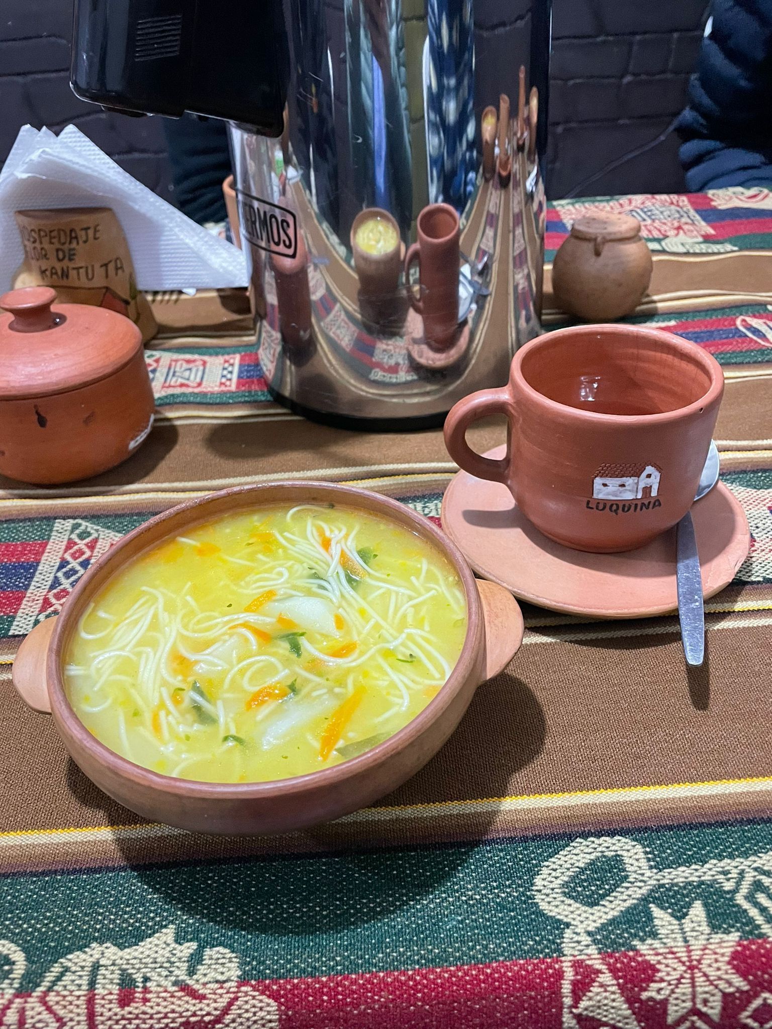 Presentació tradicional d'àpat amb un bol de sopa, una tassa i una teiera damunt d'una estora de veta.