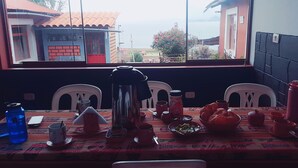 Une table à manger dressée avec différents plats et couverts, une bouteille d’eau et un téléphone intelligent.