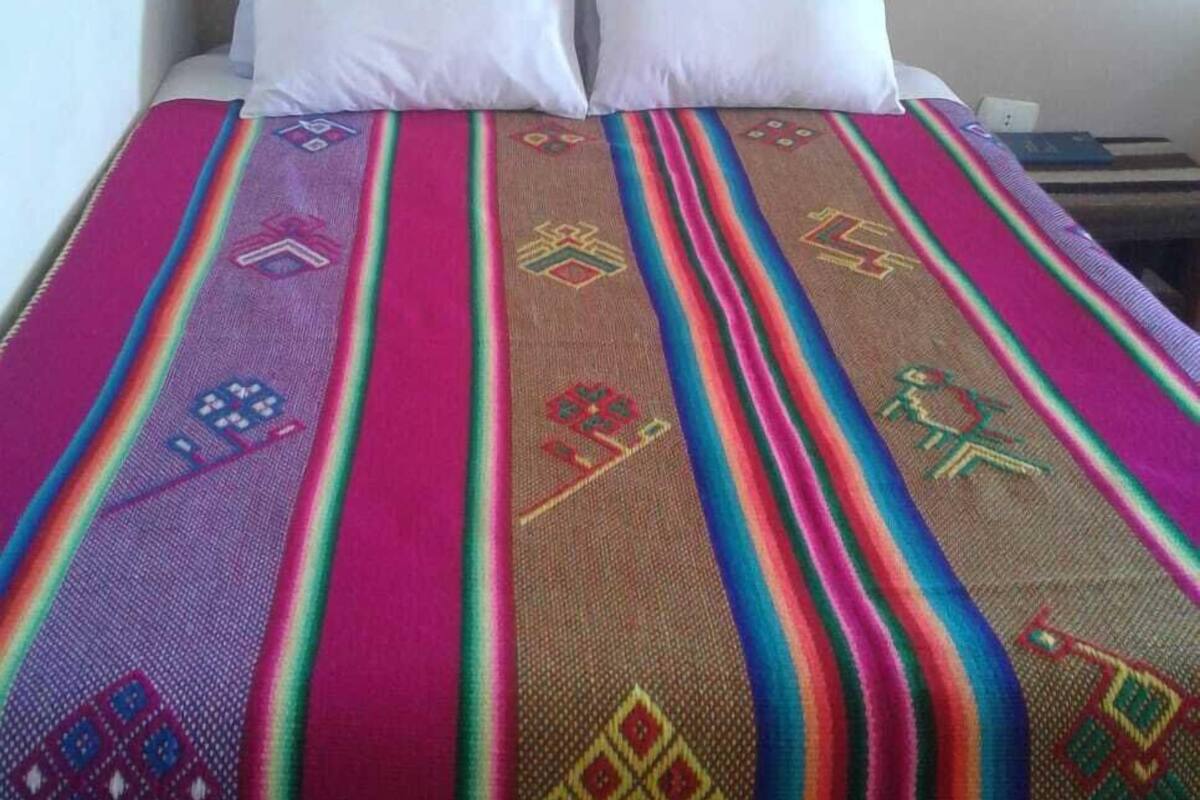 A bed with a colorful blanket and two white pillows.