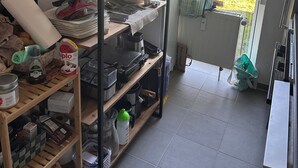 Une cuisine avec des étagères où sont rangés de la vaisselle, une bouilloire et une machine à café.