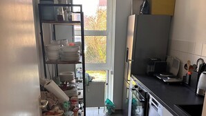 Une cuisine compacte équipée d’un lave-vaisselle, d’un réfrigérateur et d’un petit coin repas.