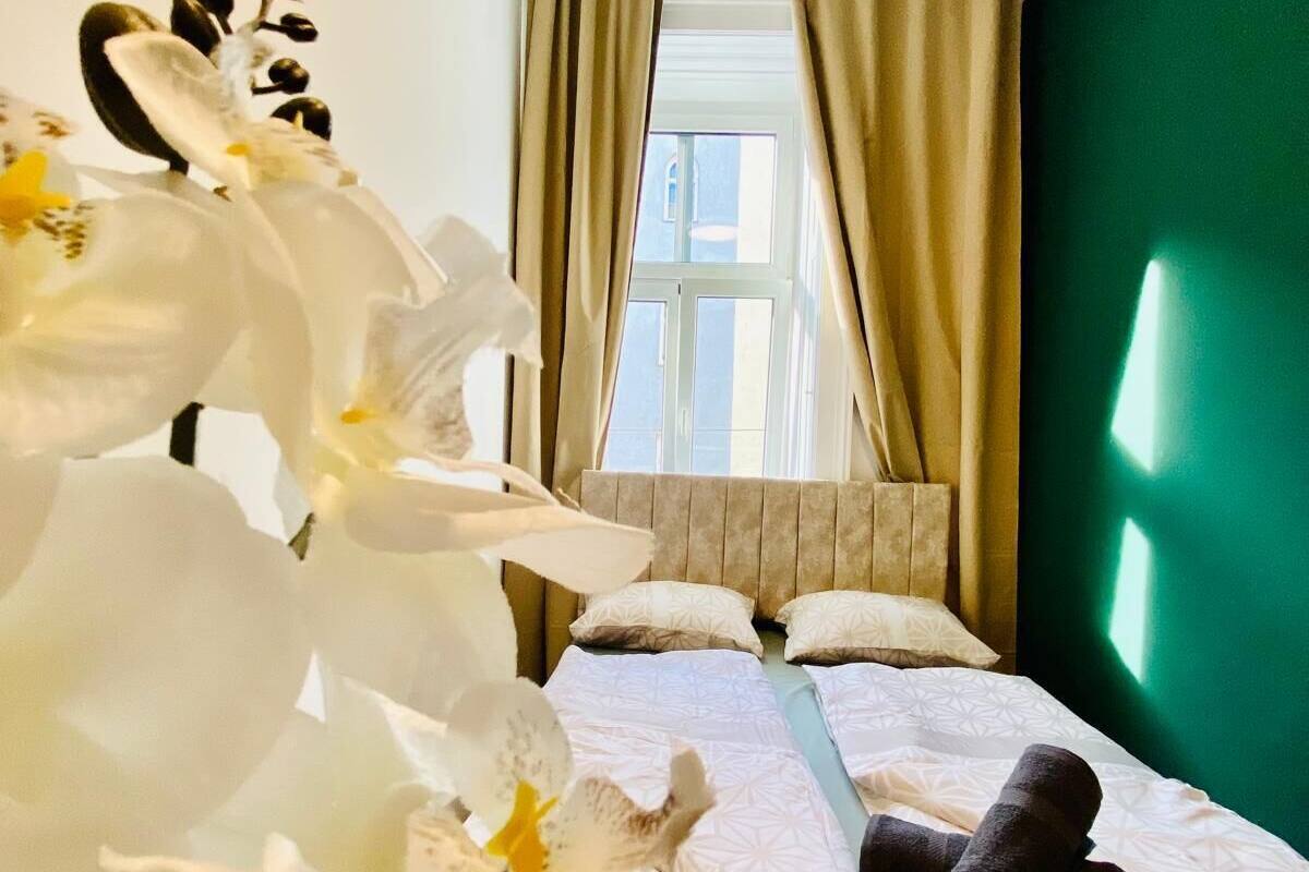 A hotel room with a bed, a window with curtains, and a green wall.