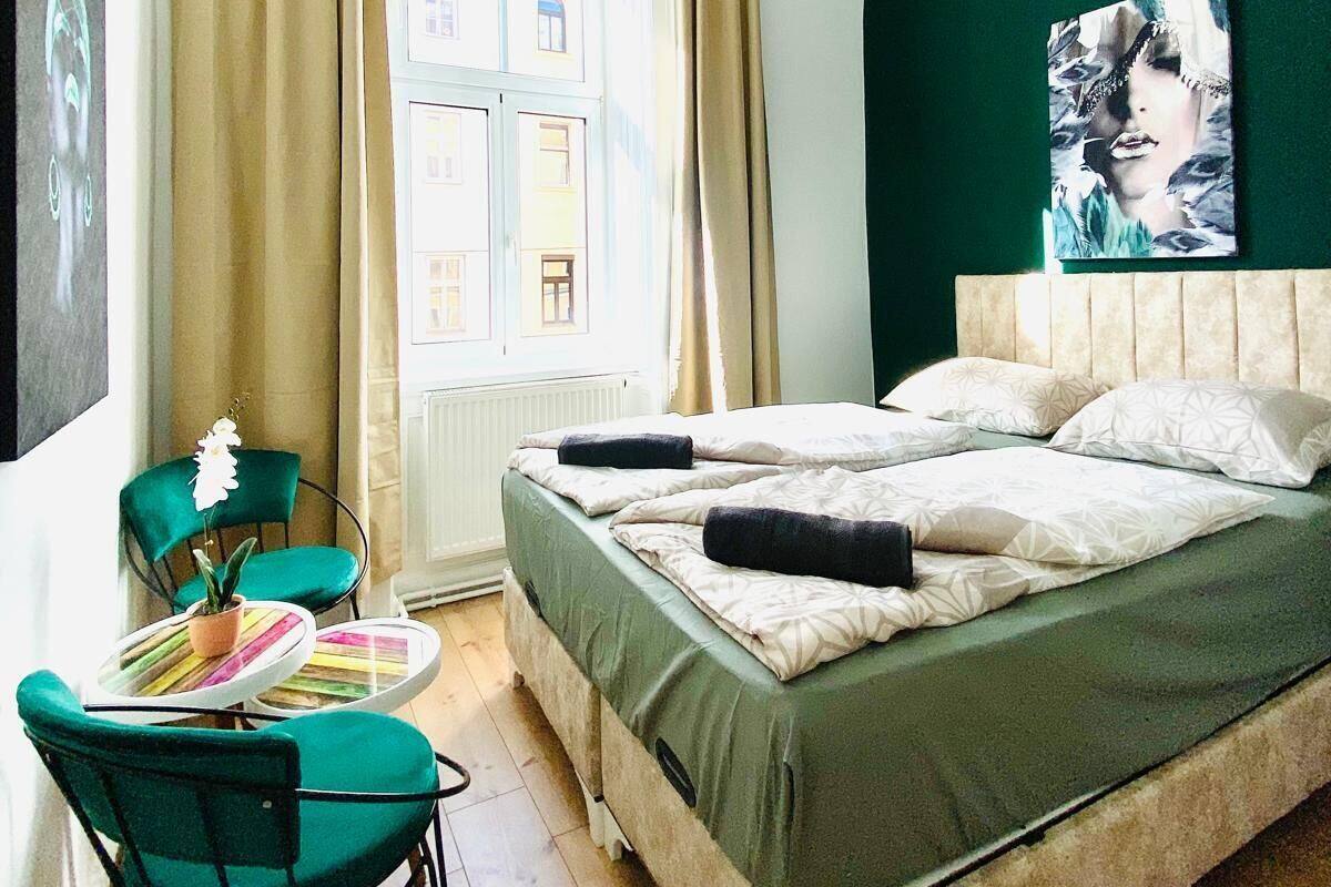 A hotel room with a large bed, a chair, a small table, and a window with curtains.