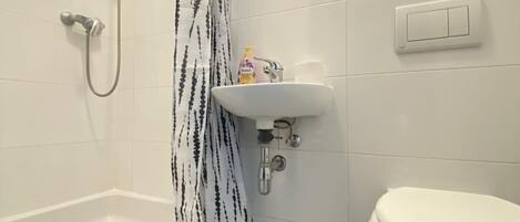 Un baño con bañera, ducha, inodoro y lavamanos.