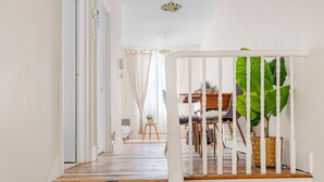 A staircase leading to a dining area with a white railing, a dining table, chairs, and a potted plant. - The Loft - Beautiful flat in Chelsea, London - Pass the Keys (London)