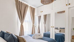 A bedroom with a large bed, two bedside tables, a wardrobe, and a mirror. - The Loft - Beautiful flat in Chelsea, London - Pass the Keys (London)