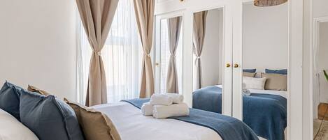 Une chambre à coucher avec un grand lit, deux tables de chevet, une armoire et un miroir.