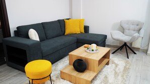 A modern living room with a sectional sofa, a yellow ottoman, a wooden coffee table, and a grey armchair. - Athenian Petralona Suite (Athens)