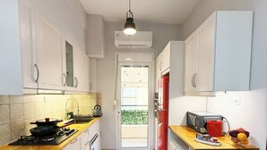 A modern kitchen with white cabinets, a wooden countertop, a red refrigerator, and a potted plant. - Athenian Petralona Suite (Athens)