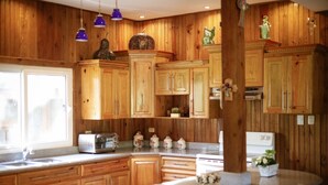 A kitchen with wooden cabinets, a toaster, a stove, and hanging pendant lights.