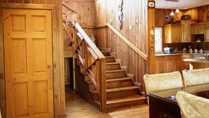 A wooden interior with a staircase leading to a kitchen area.
