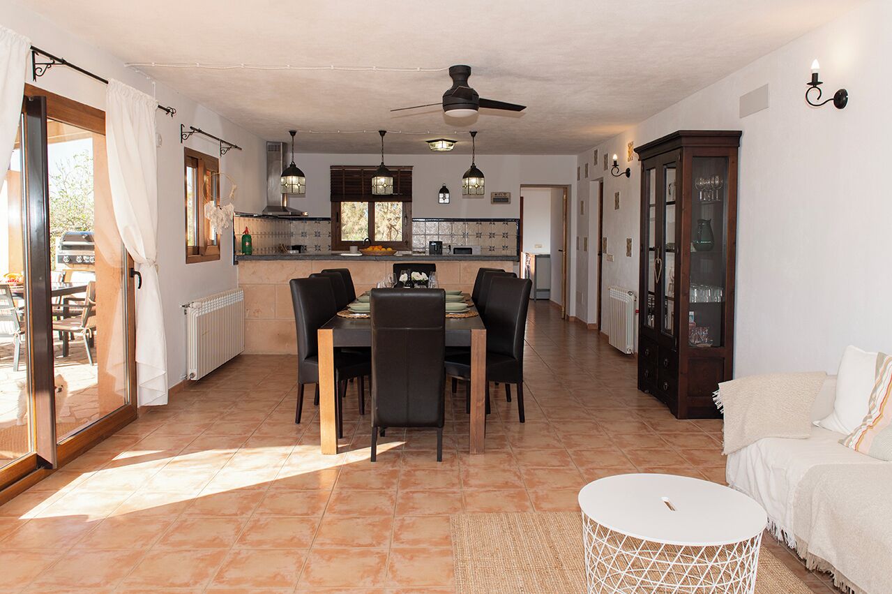 A spacious living area with a dining table, chairs, a sofa, and a cabinet.