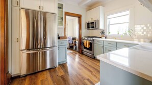 A modern kitchen with stainless steel appliances, light blue cabinets, and a wooden floor.