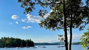 A wooden dock extending into a calm lake with boats anchored nearby.