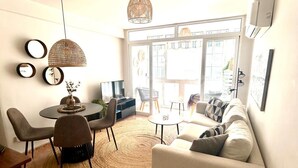 A living room with a round dining table, a sofa, and a TV. - Casa Caramona - Two Bedroom Apartment, Sleeps 4 (Nerja)