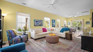 A spacious living room with a white sofa, colorful cushions, a patterned rug, and a ceiling fan. - Quiet Retreat, Golf Cart Included, Pet Friendly - 603 Porpoise (Fripp Island)