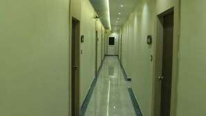 A long, narrow hotel corridor with doors on both sides, a tiled floor, and recessed lighting on the ceiling. - Hotel Greenland (Khammam)