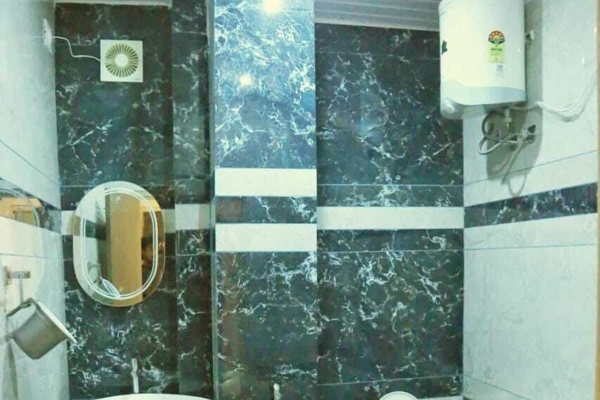 A bathroom with a sink, mirror, toilet, and a water heater.