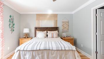 Een slaapkamer met een bed, nachtkastjes, een lamp, een decoratie aan de muur en een deur.