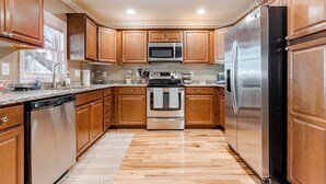Una cocina moderna con armarios de madera, electrodomésticos de acero inoxidable y encimera de granito.