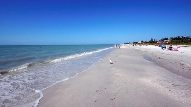 A beach with a clear sky, calm sea, and people relaxing on the sand. - Perfect Beach Vacation -Sanibel Island's Loggerhead Cay 234 (Sanibel)
