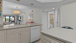 A modern kitchen with white cabinetry, a dishwasher, and a large island.