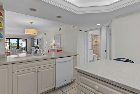 A modern kitchen with white cabinetry, a dishwasher, and a large island. - 2 Bedroom Condo With Spectacular Gulf Views (Sanibel)