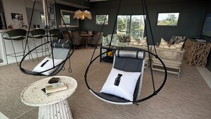 Amplia sala de estar con techo alto, una silla colgante, una mesa redonda y un sofá.