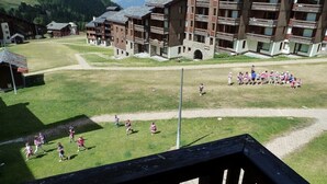 A group of children playing on a grassy field with a building in the background.