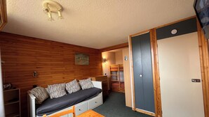 A cozy room with a wooden wall, a bunk bed, a desk, and a wardrobe.