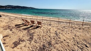 Una playa con hileras de sillas de playa vacías y una vista despejada del océano.