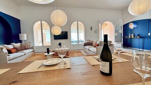 Una sala moderna con una mesa de comedor de madera dispuesta para dos personas, una botella de vino y un televisor montado en la pared.