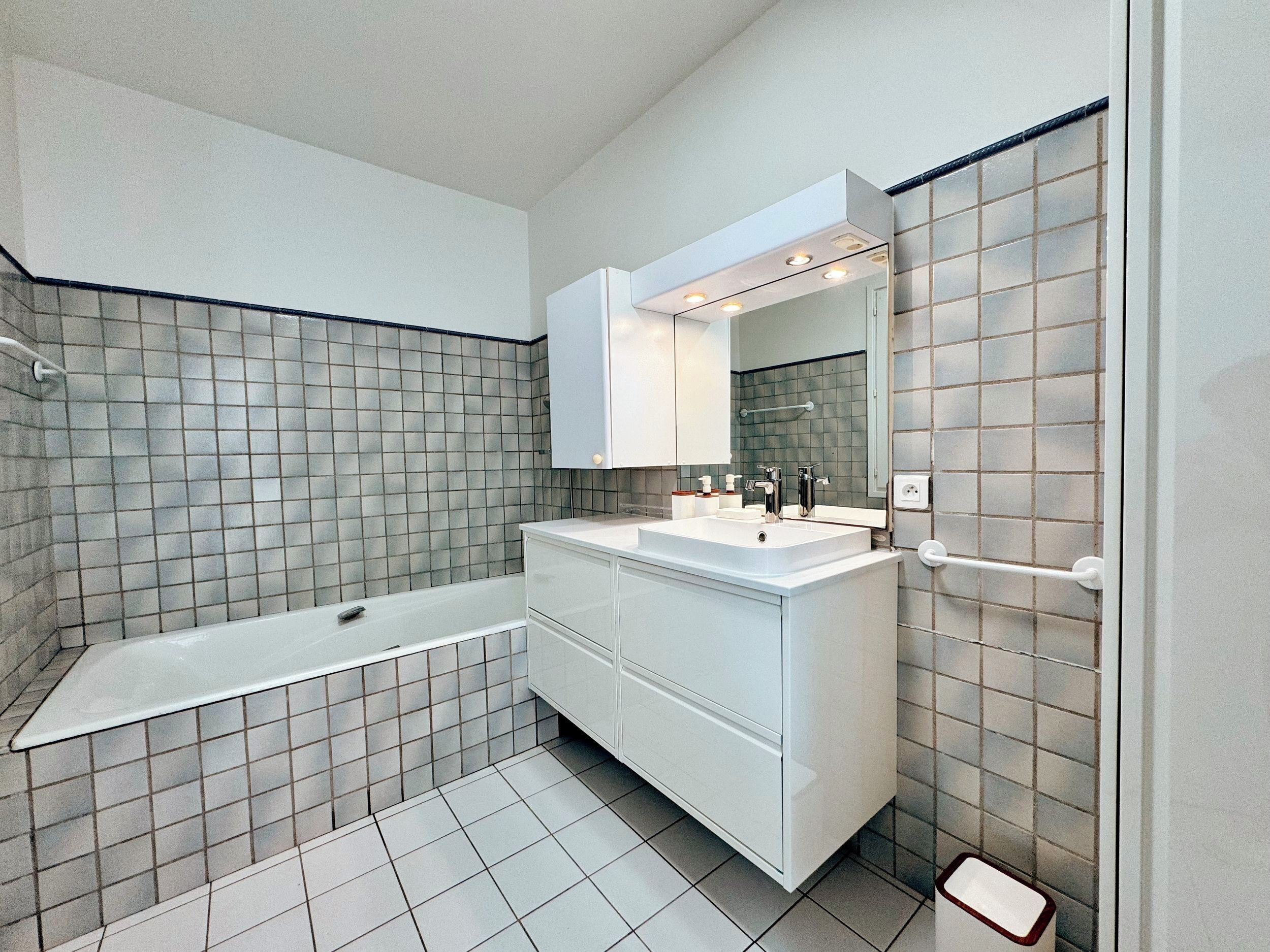 Un bagno moderno con vasca, doppio lavabo e un grande specchio.