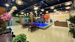 Vestíbulo de hotel con mostrador de recepción, zona de estar y una pequeña piscina interior.