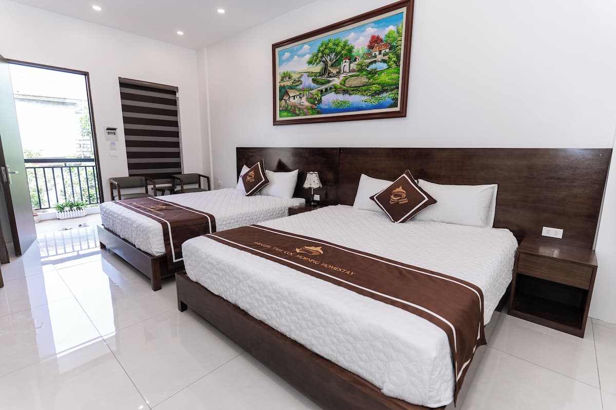 A hotel room with two beds, a painting on the wall, and a balcony.