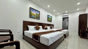 Habitación de hotel con dos camas, cabecero de madera, ropa de cama blanca y dos cuadros con paisajes en la pared.
