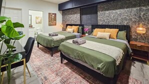 Ein modernes Schlafzimmer mit zwei Betten, einem Essbereich und einer großen Pflanze.