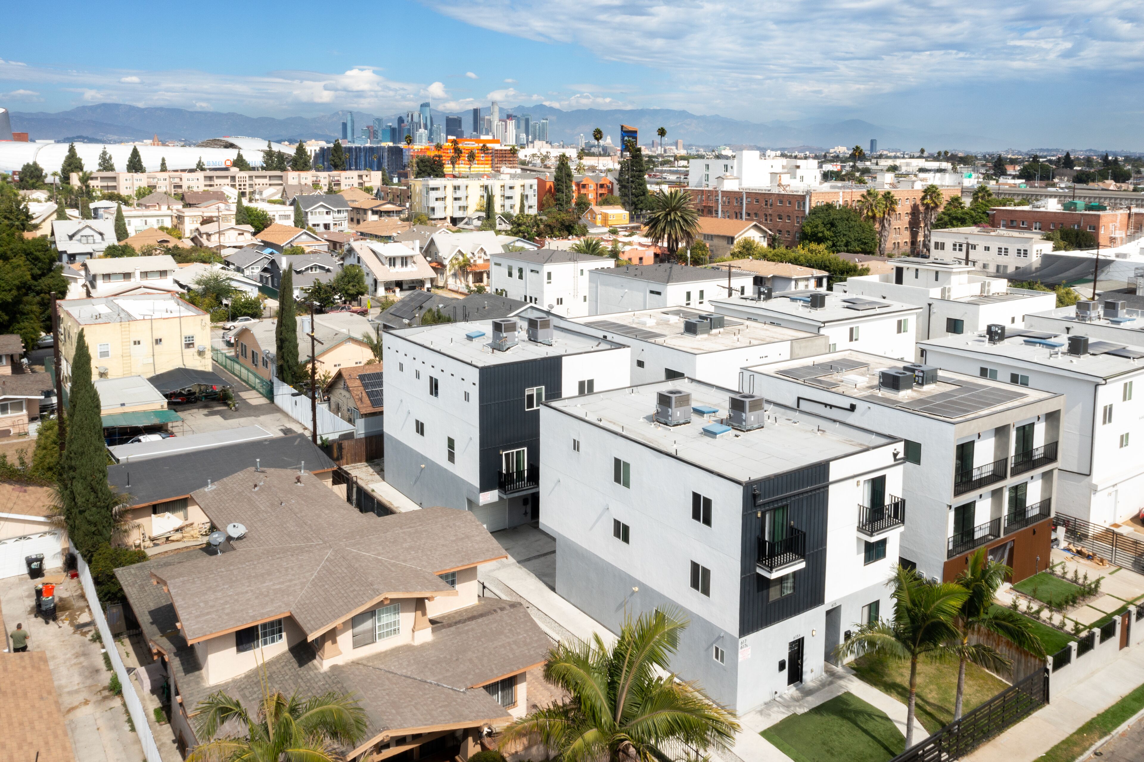 Un quartier résidentiel avec des immeubles d’appartements modernes, dont certains sont dotés de balcons, et une vue sur les gratte-ciel de la ville en arrière-plan.