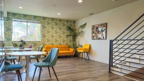 Un salon moderne avec un plancher en bois, un canapé orange vif et un escalier doté d’une rampe en métal.