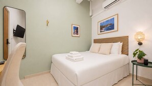 A hotel room with a bed, a chair, a bedside table with a lamp, and a wall-mounted TV. - Room 9: Sleek & Serene Stay in San Juan (San Juan)