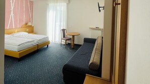 A hotel room with a bed, a sofa, a small table, and a chair. - Enrosadira (Predaia)