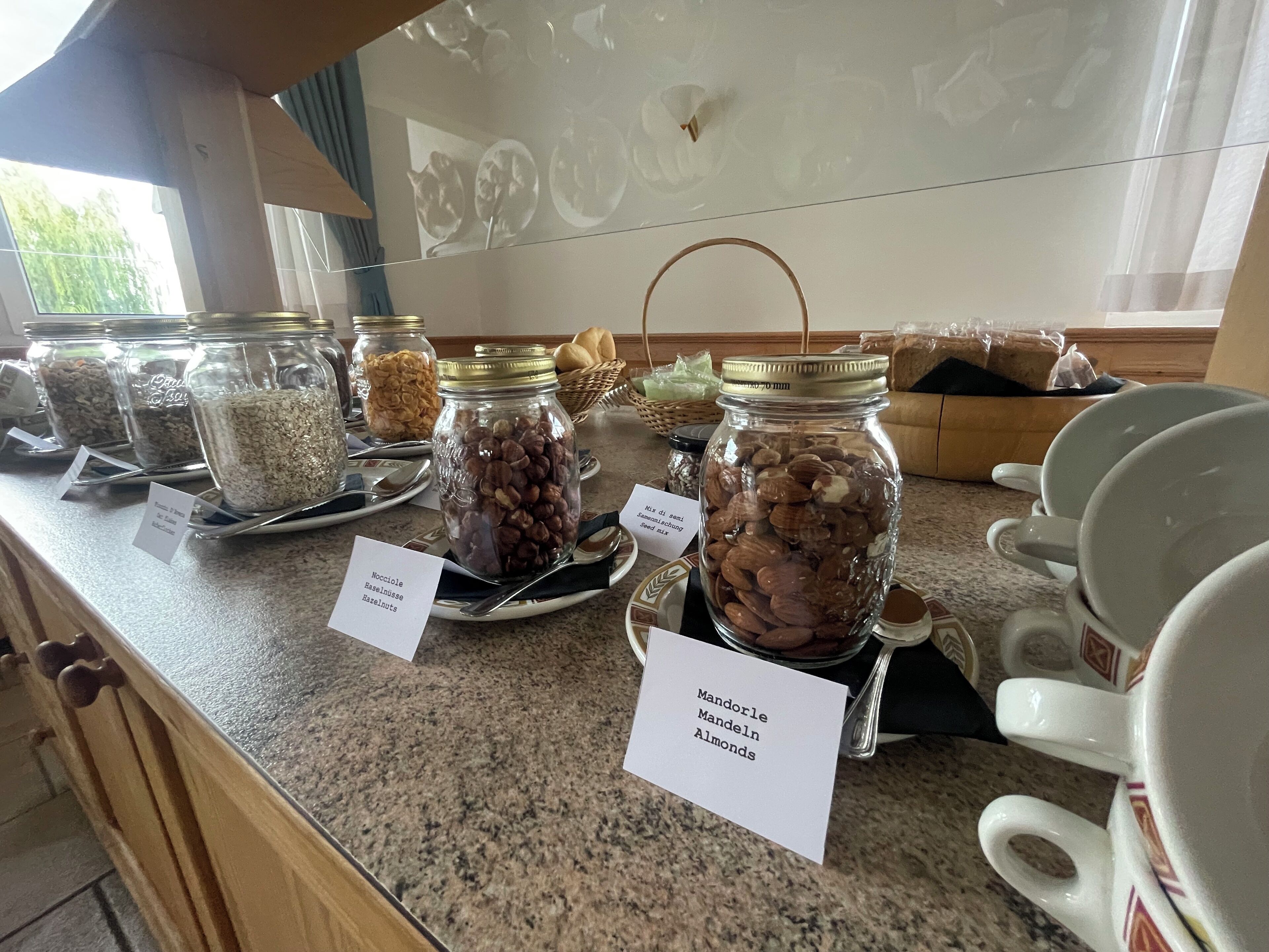 A buffet counter with various food items in jars labeled with their contents, such as nuts and seeds.