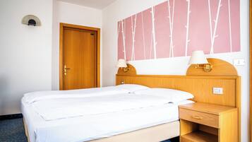 Ein Hotelzimmer mit einem Bett, einem Holzkopfteil, Nachttischlampen, einem Nachttisch und einer Wand mit Baummuster.