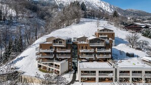 Une station de ski moderne avec des bâtiments à plusieurs étages dotés de balcons et d’espaces de détente en plein air.