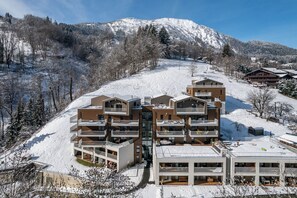 A modern ski resort with multi-story buildings featuring balconies and outdoor seating areas.